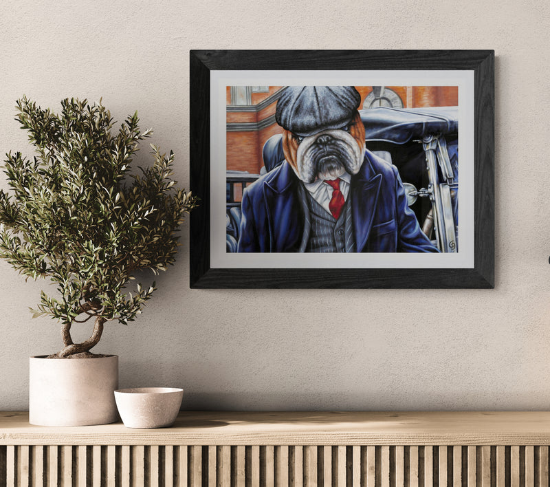 Framed artwork of a bulldog in a suit on a wall above a wooden console table with decorative items.