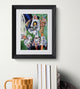 Framed artwork of a fantastical cat creature on a white wall with books and a mug below.