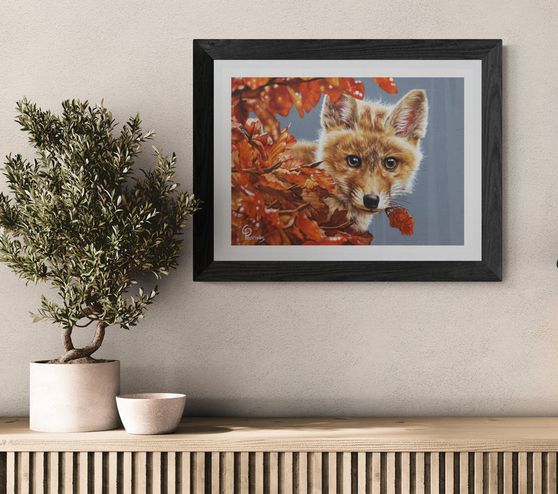Framed artwork of a fox surrounded by autumn leaves on a wall above a wooden console table.