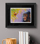 Framed artwork of a monkey and butterfly on a gray wall with books and a mug below.
