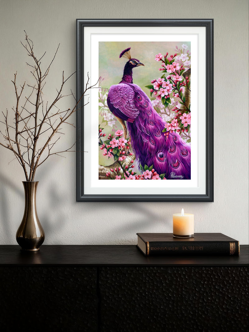 Framed artwork of a purple peacock among flowers on a wall above a dark surface with a candle and vase.