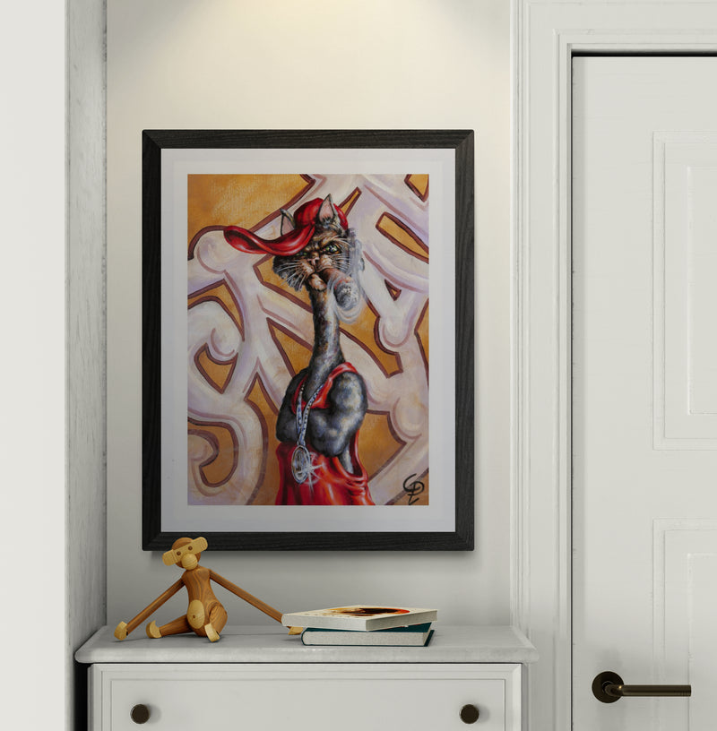 Framed artwork of a stylized cat figure with a red cape on a white wall.