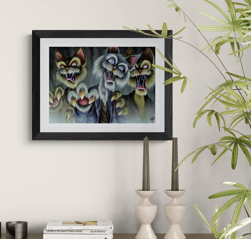 Framed artwork of three anthropomorphic zombie cats on a wall with decorative elements.