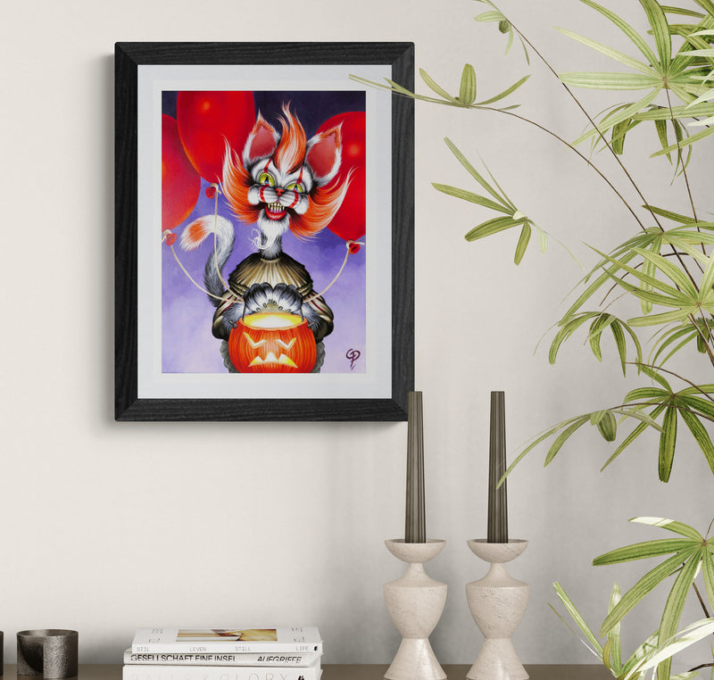 Framed artwork of a stylized cat-like creature with red eyes and orange hair on a white wall.