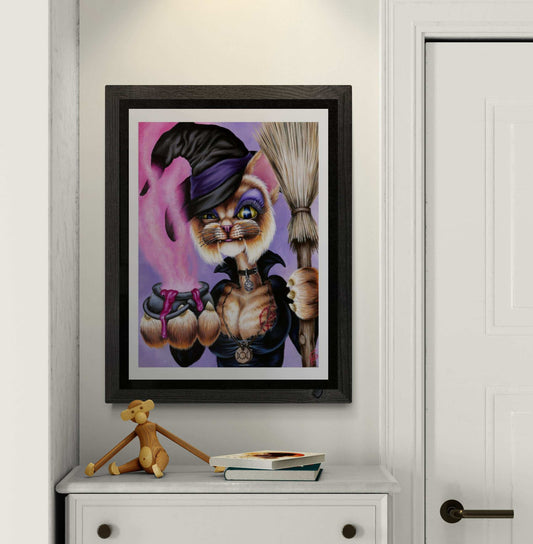 Framed artwork of a cat in a witch costume on a white wall.