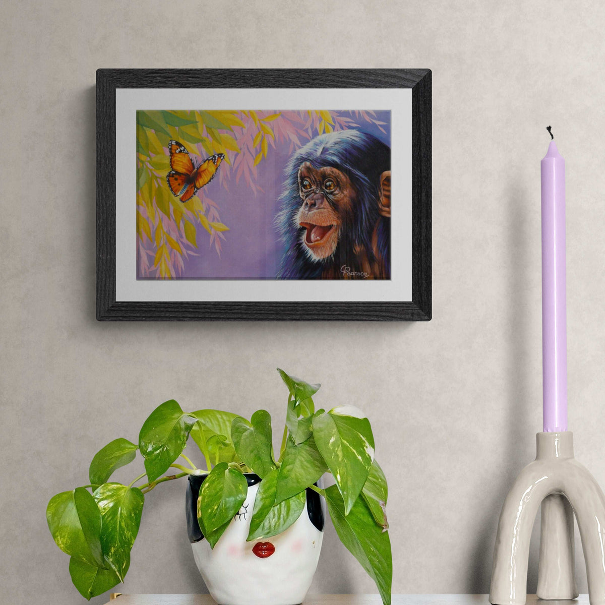 Framed artwork of a monkey and butterfly on a wall with decorative items below.