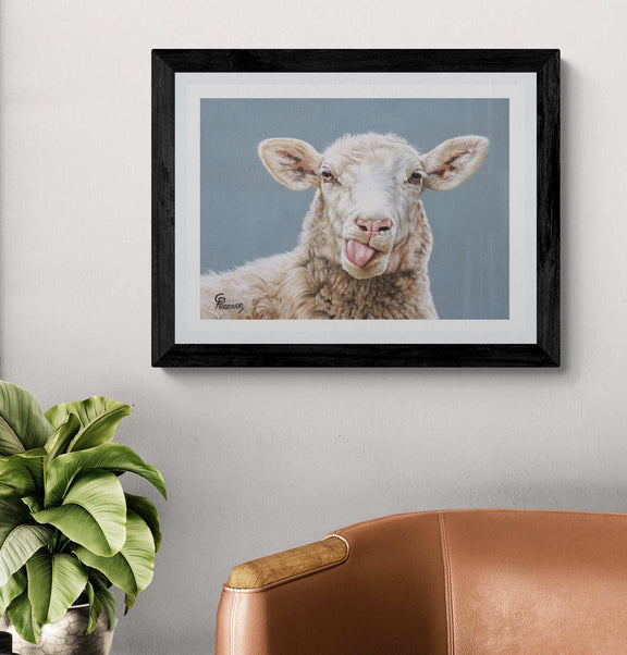 Framed artwork of a sheep with a tongue sticking out on a wall above a brown chair and plant.