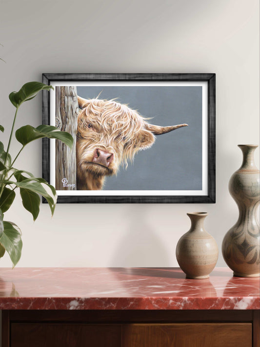 Framed picture of a Highland cow on a wall above a wooden cabinet with vases.