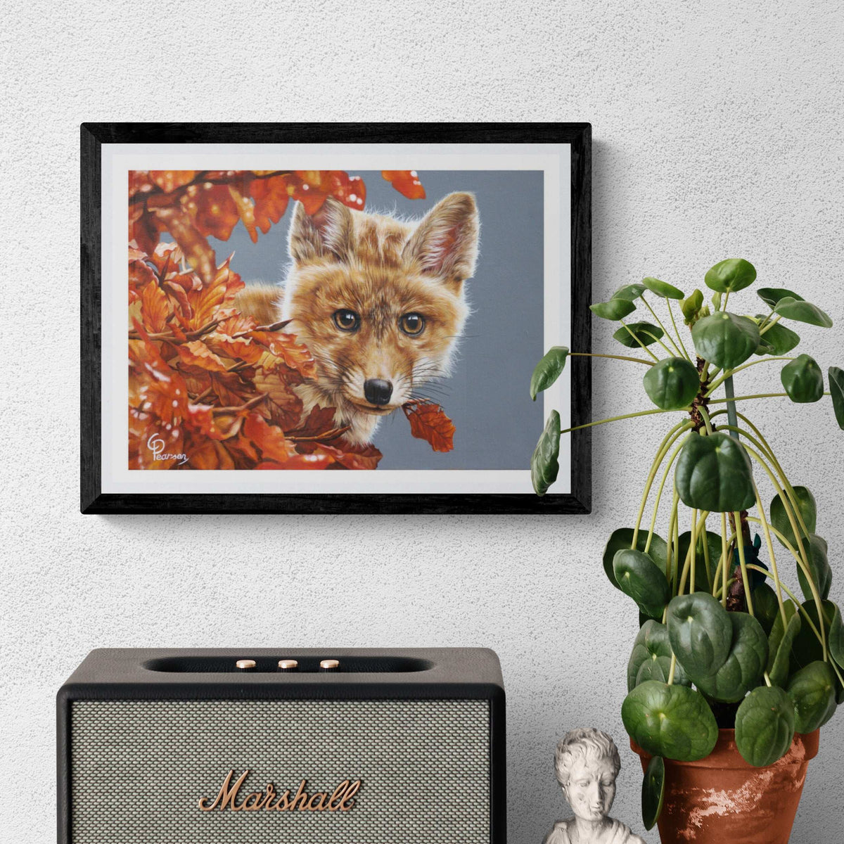 Framed picture of a fox among autumn leaves above a Marshall speaker on a wall.