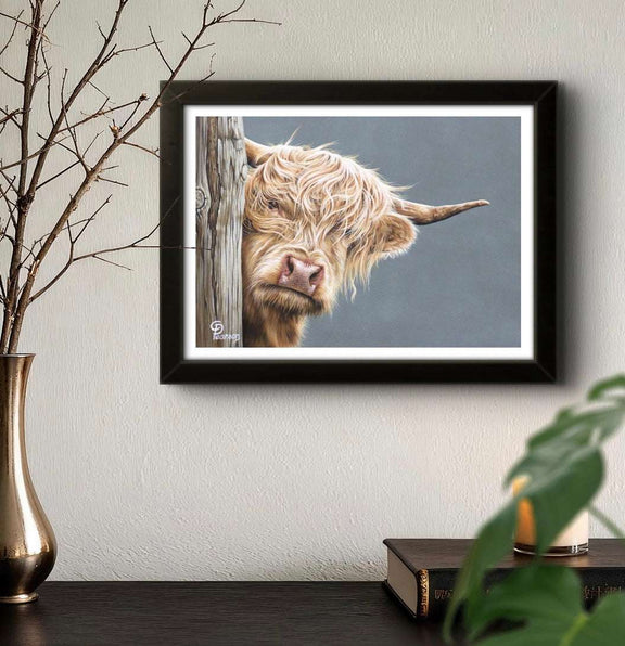 Framed picture of a highland cow on a wall with decorative elements.