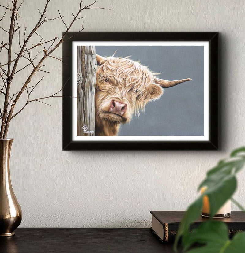 Framed picture of a highland cow on a wall with decorative elements.