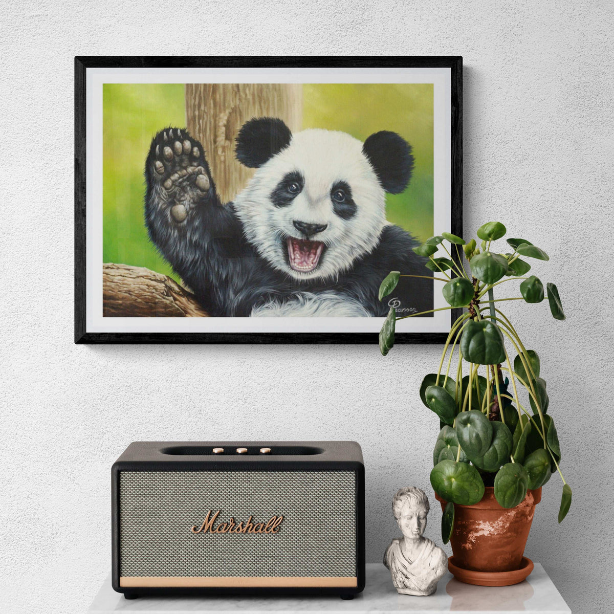 Framed picture of a panda, Marshall speaker, plant, and small statue on a white surface.