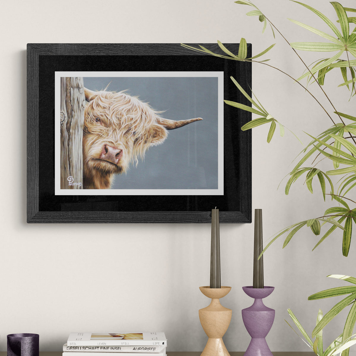 Framed artwork of a Highland cow peeking from behind a log on a wall with decorative elements.