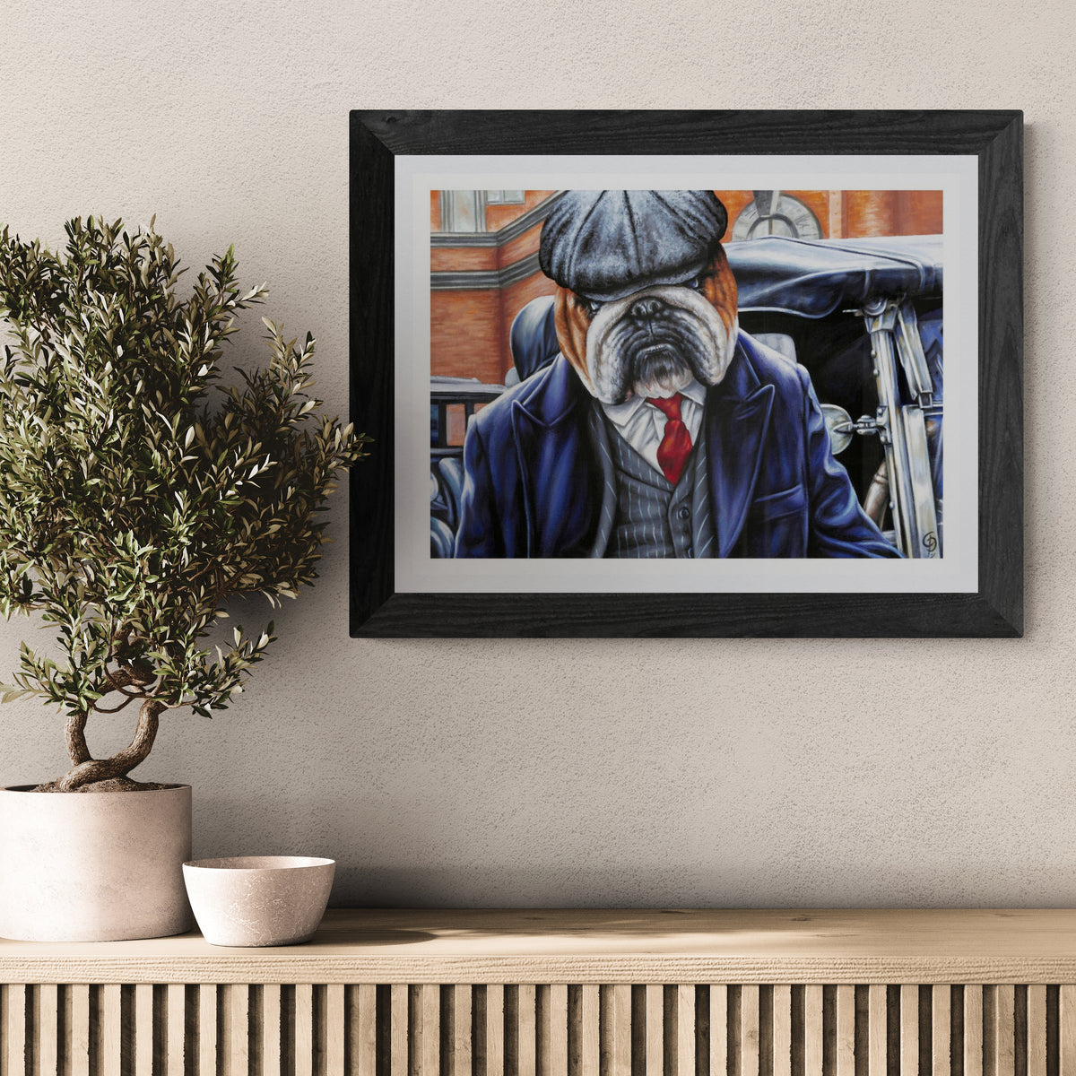 Framed artwork of a bulldog in a suit on a wall above a wooden console table with decorative items.