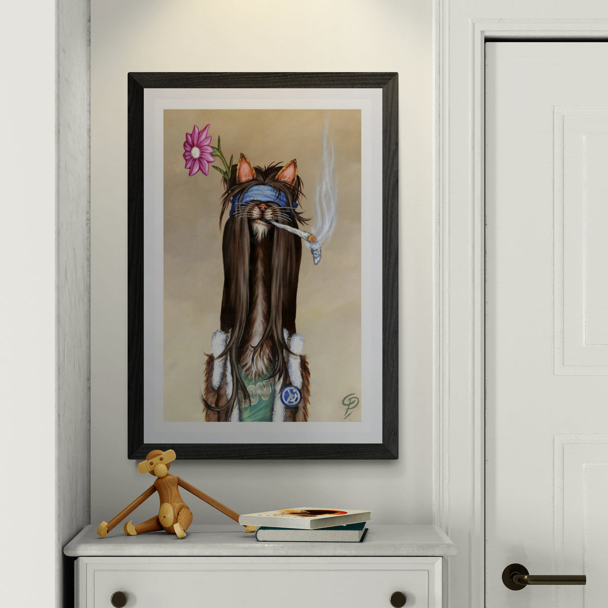 Framed artwork of a cat with a flower on a wall above a white cabinet.