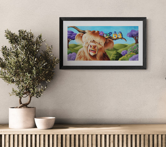 Framed artwork of a cow with a butterfly on a wall above a wooden shelf with a plant and bowl.