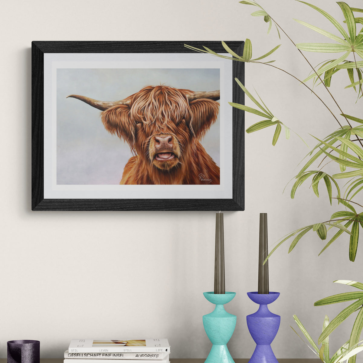 Framed artwork of a highland cow on a wall with decorative vases and plants.