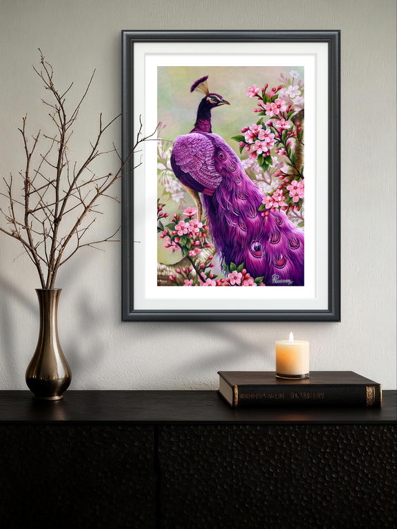 Framed artwork of a purple peacock among flowers on a wall above a dark surface with a candle and vase.