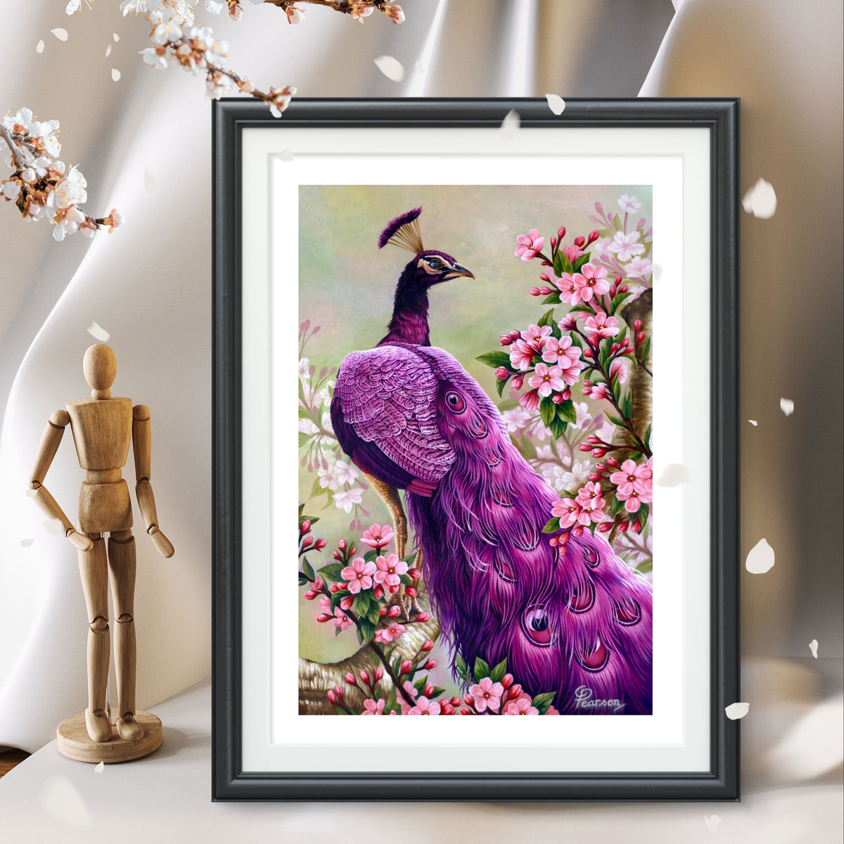 Framed artwork of a purple peacock among flowers on a white surface with a wooden mannequin and cherry blossoms.