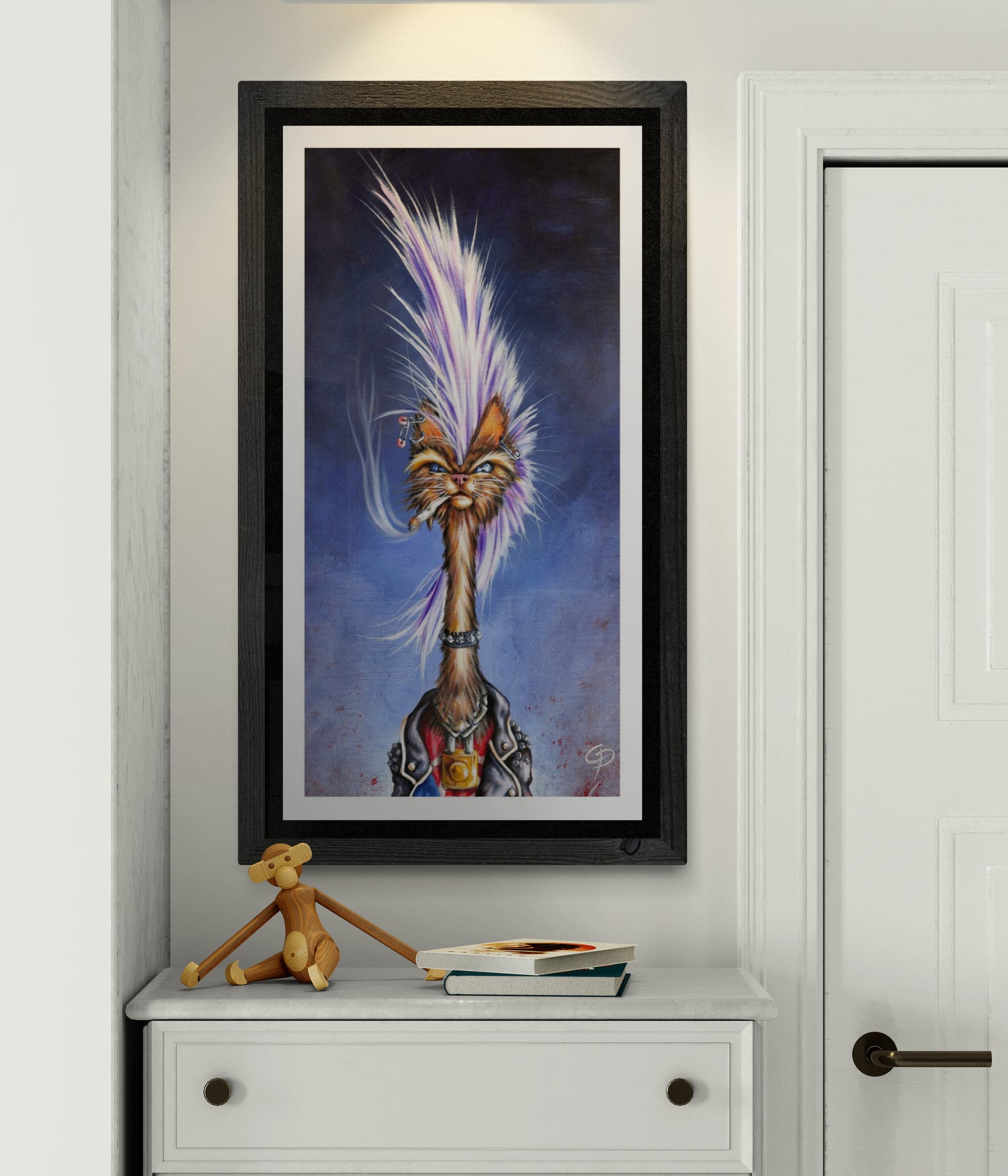 Framed artwork of a stylized cat with a feathered headdress on a white wall.