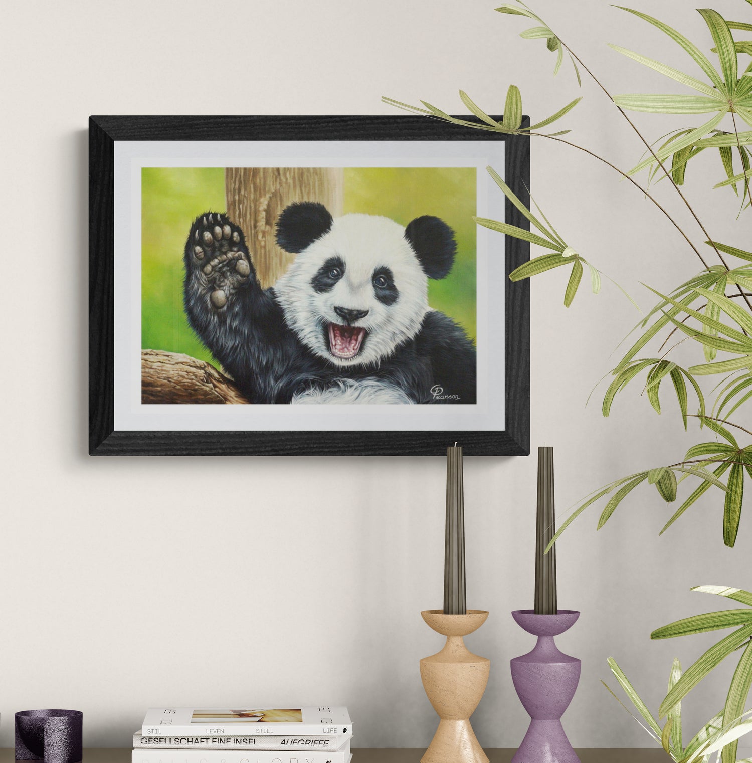 Framed painting of a panda bear on a wall with decorative candles and books below.