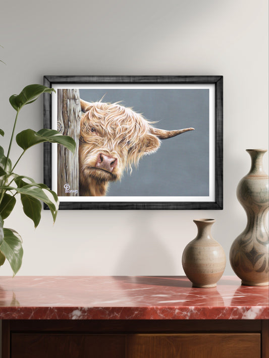 Framed picture of a Highland cow on a wall above a wooden cabinet with vases.