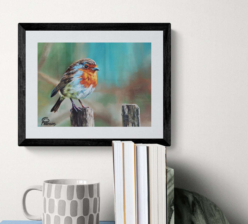 Framed artwork of a bird on a wooden post with books and a mug below.