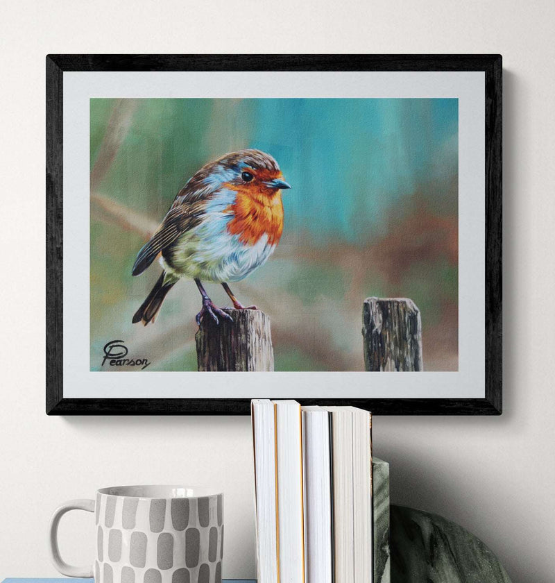 Framed painting of a robin on a wooden post with books and a mug below.